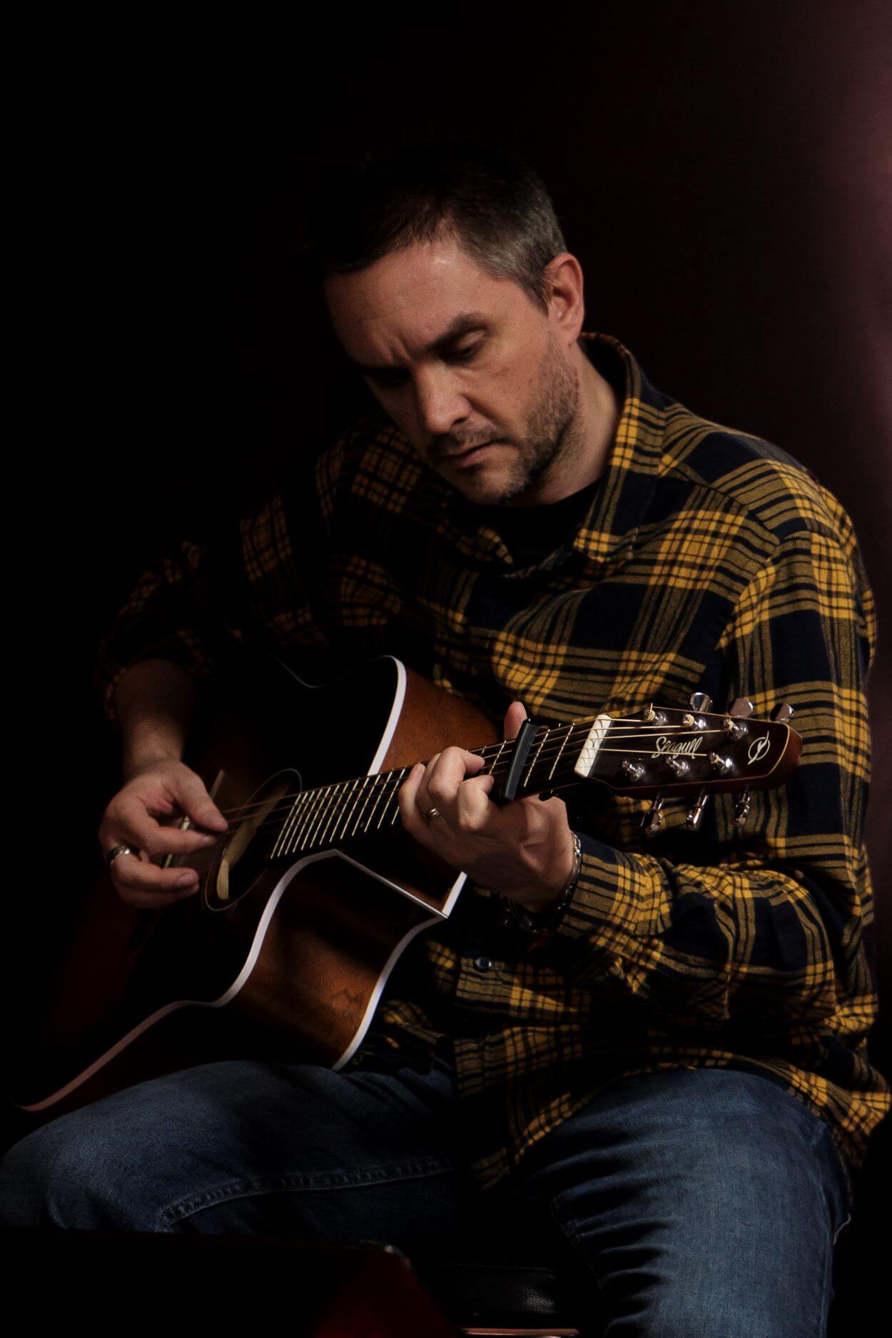 Élève adulte jouant de la guitare acoustique lors d'un spectacle organisé pour les membres de l'association Améthyste.