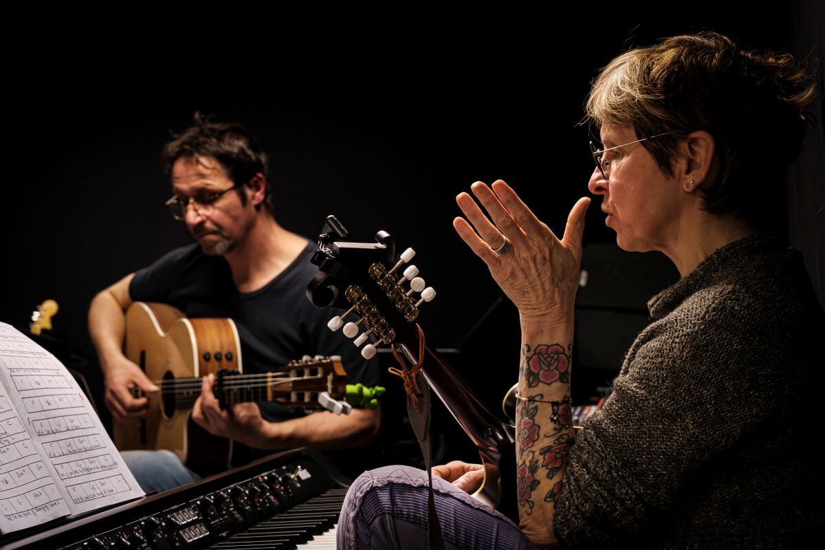 Professeur de guitare et professeur de chant de l'association Améthyste travaillant un morceau tout en discutant, avec leurs instruments en main, lors de stages de musique.